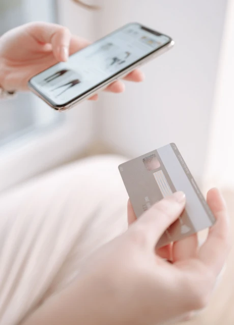Person using a smartphone while holding a payment card
