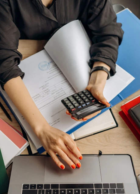 Person using a calculator while reviewing financial documents