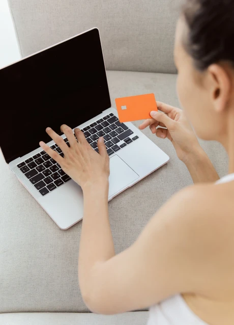 Person using a laptop while holding a payment card