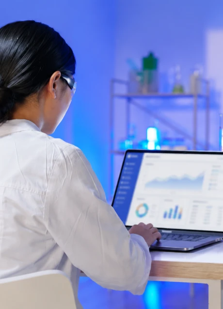 Healthcare professional reviewing data dashboards on a laptop in a laboratory