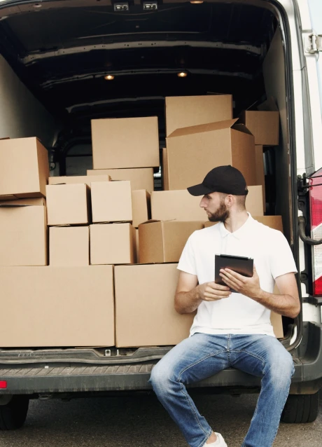 Delivery worker reviewing shipment information on a tablet beside a loaded vehicle