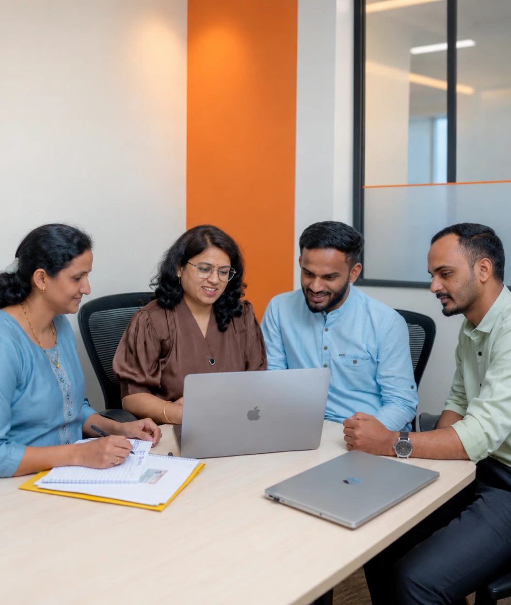 Team discussing business challenges around a laptop
